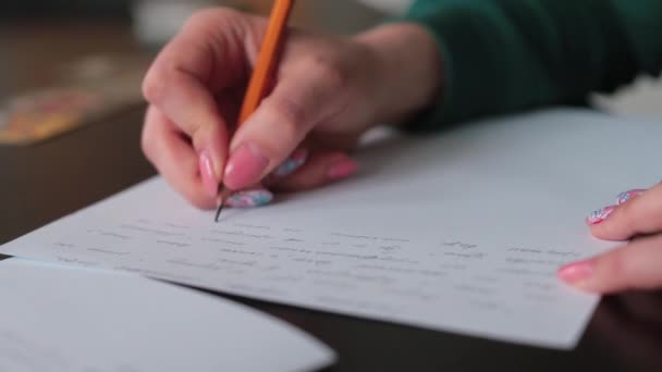 Weibliche Hand schreibt Text mit Bleistift auf Papier. Gedanken in Textform formulieren. — Stockvideo