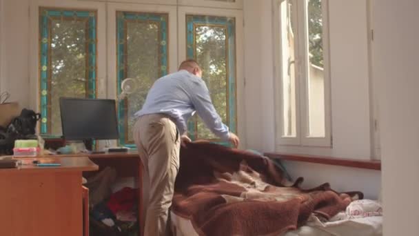 Omul face patul în cameră. Afaceri de dimineaţă după subţiere. Tidying up room. — Videoclip de stoc