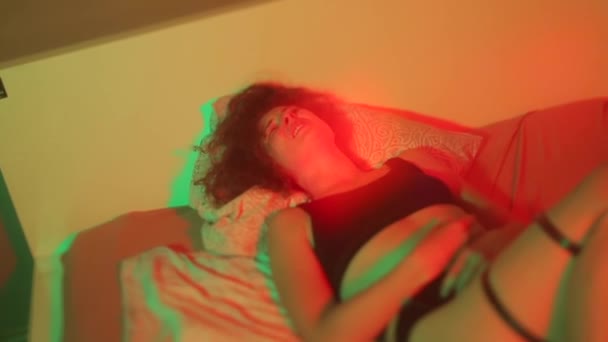 Stressed woman lies on bed in red light She lives emotion, relaxes body — Stock Video