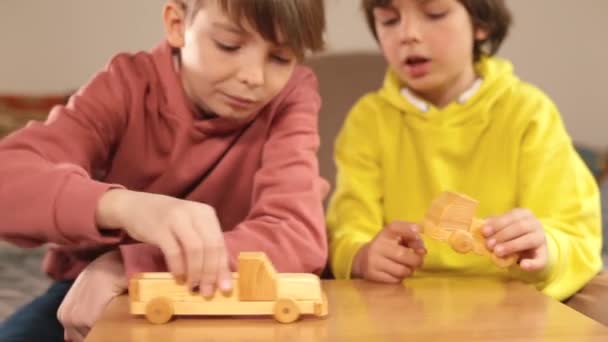 Due fratelli stanno giocando con giocattoli fatti a mano in legno. Prova di nuove auto giocattolo. — Video Stock