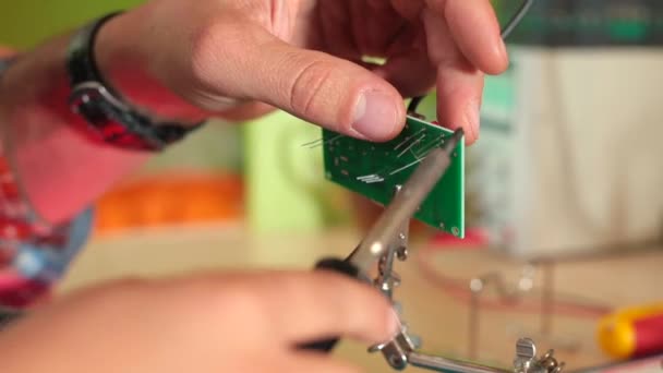 Mãos masculinas anexam peças à placa eletrônica, fixação a quente usando ferro de solda — Vídeo de Stock