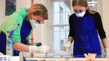 İki yetenekli maskeli sanatçı epoksi resim yapıyor. Yığınla malzeme kullanarak çalış.