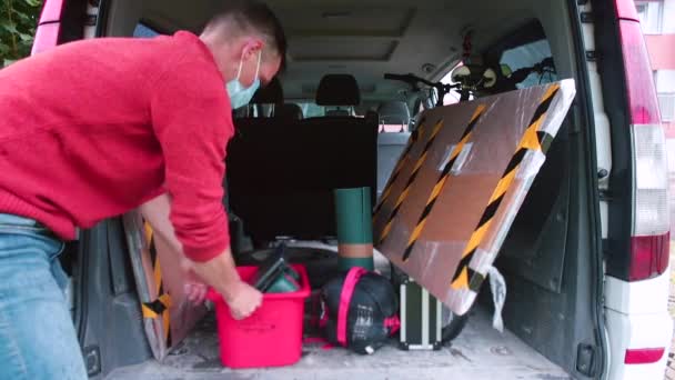 Maskierter Mann trägt Ladung aus Kofferraum Er nimmt Gegenstände in die Hand und entlädt sie — Stockvideo