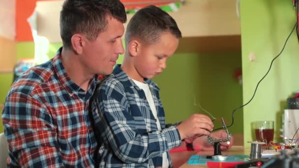 Boy makes hot joint using soldering iron looks magnifying glass, quality control — Stock Video