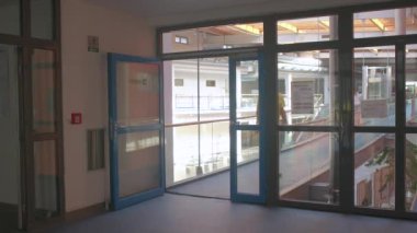 Çalışan koridorda kapıdan içeri giriyor. Cam kapılar. İki numaralı oda.