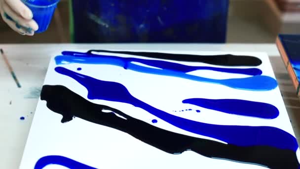 Artista derrama tinta azul na superfície. Fazer uma pintura a partir de materiais fluidos. — Vídeo de Stock