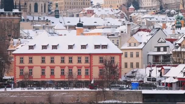 Toeristische uitzicht winter stad Praag huizen dijk sneeuw ligt op de daken. — Stockvideo