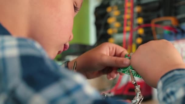 Jongen hecht deel elektrische bordtafel Hij maakt primitief elektrisch apparaat — Stockvideo