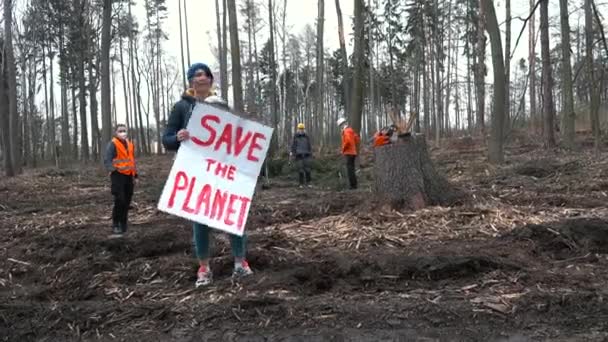 Femme avec bébé en veste, affiche lit Save planet sur un site d'abattage. — Video