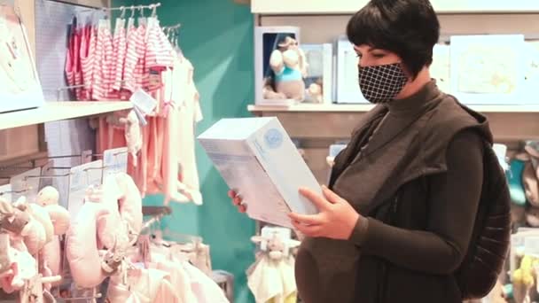 Une femme enceinte en vêtements noirs choisit des marchandises dans un magasin. — Video