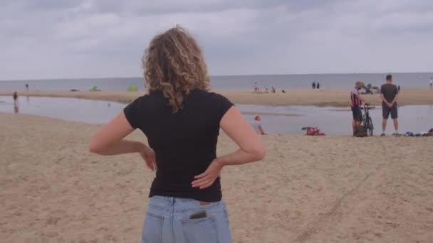 Kvinna med hår ner stående strand nära havet. Hon tittar på avstånd, drömmar. — Stockvideo