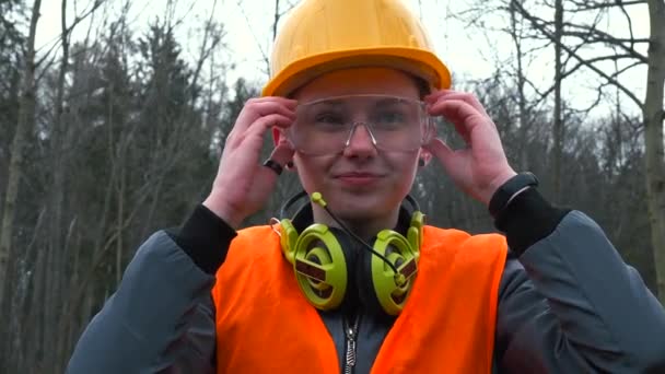 Pekerja potret dengan kacamata, topi keras. Headphone dipakai di sekitar leher. — Stok Video