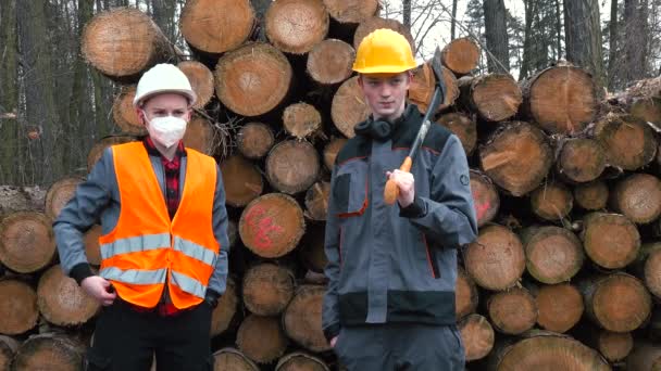 Retrato de los trabajadores sobre el fondo de los troncos. Uno con una máscara en la cara. — Vídeo de stock