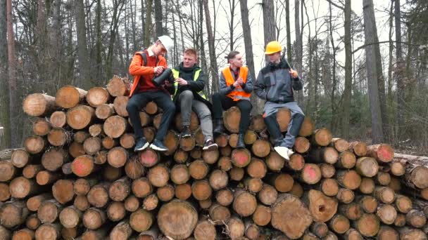 Rest group workers sawmill. They sit on stacked logs Pours tea, smokes — Stock Video