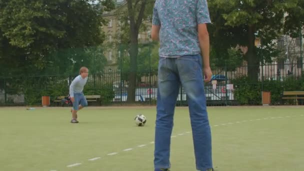 Down síndrome menino chuta bola de futebol, ele corre goleiro bate bola — Vídeo de Stock