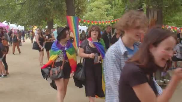 Dos personas en el desfile LGBT en el parque urbano. Ella muestra un gesto, encantada de conocerla. — Vídeos de Stock