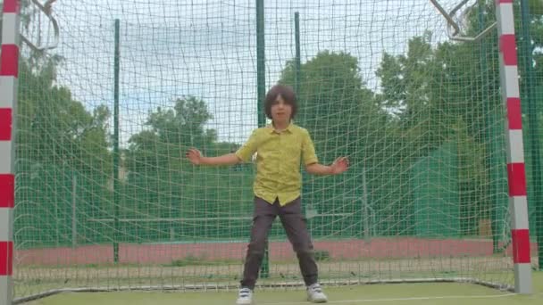 Adolescent aux cheveux longs se tient but de football Prépare coup fait des mouvements du corps — Video