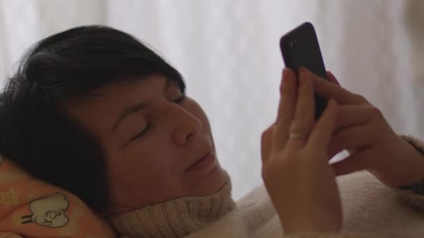 Женщина использует мобильный телефон руки лежа кровать Свободное время домашний экран гаджет — стоковое видео