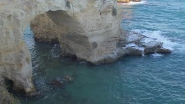 Uçurumdaki doğal taş kemerden denize hayran turistler, Torre Sant Andrea.