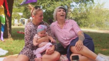 Bebekli aile. Şehir parkında piknik yaparken küçük çocuklu mutlu LGBT çifti.