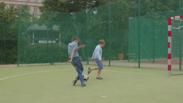 Tieners spelen bal op het voetbalveld. Down syndroom jongen vangt een bal. — Stockvideo