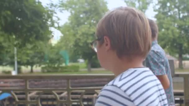 Подросток с синдромом Дауна ходит по тротуару в городском парке — стоковое видео