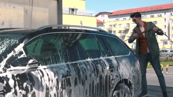 Man wast schuim uit auto met behulp van hoge druk spray fles Voorbereiding van voertuig reis — Stockvideo