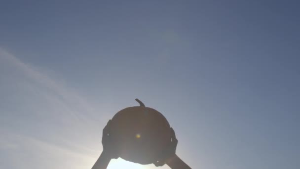 Harvest festival celebration. Silhouette of a pumpkin in hands. — Stock Video