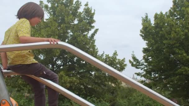 Tiener rolt op een pijp in een stadspark met behulp van een glijbaan. Het wordt met de hand vastgehouden. — Stockvideo