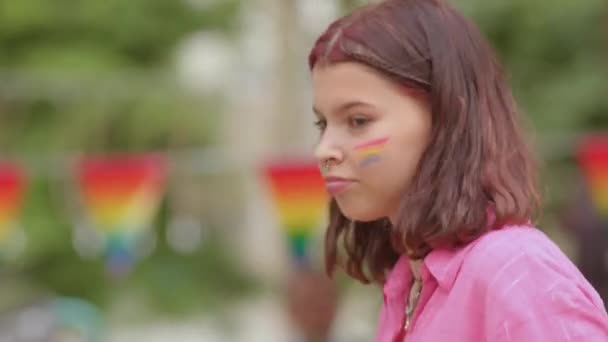 Портрет девушки с изображением ЛГБТ-флага на щеках Она танцует, машет телефоном — стоковое видео