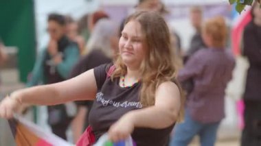 Kız LGBT bayrağını açar ve kafaya bağlar. Bayrak içinde gösteri sembolü.