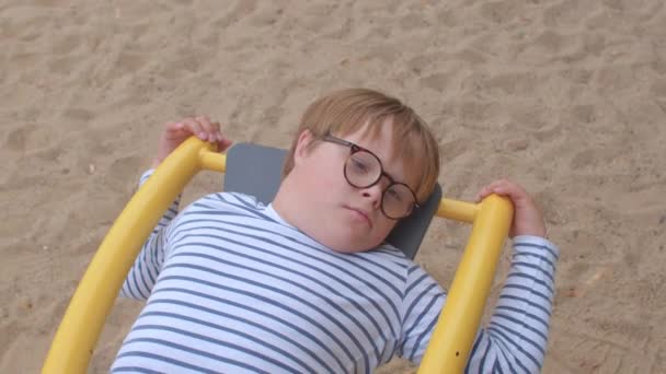 Retrato menino baixo síndrome óculos criança balanço mentiras Restaurando força — Vídeo de Stock