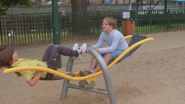 Tieners rijden een schommel in een stadspark. Ze gebruiken hun eigen gewicht in beweging. — Stockvideo