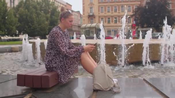 La mujer está ansiosa usando el teléfono en la fuente de la ciudad.. — Vídeo de stock