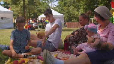 Büyük aile boş zamanlarını şehir parkında geçirir. Meyve bırakır, boş zamanlarını motive eder.