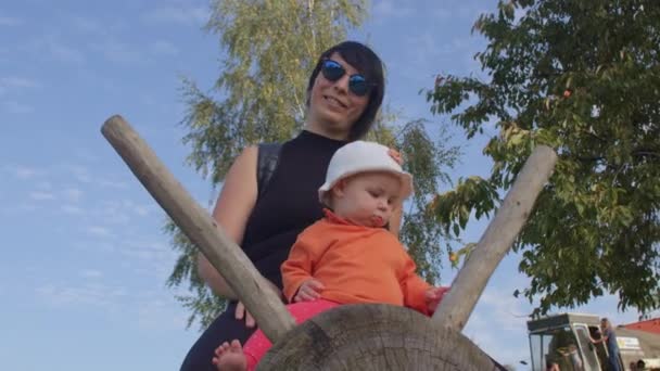 Porträtt av mamma och dotter i naturen. Baby i orange tröja och vit panama. — Stockvideo