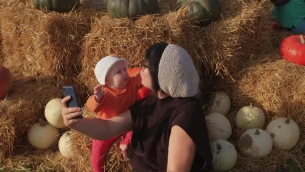 Bebé en suéter naranja y panama. Mamá con hija, tatuaje, gafas de sol, teléfono. — Vídeos de Stock