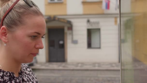 Junge Frau schaut an Haltestelle des öffentlichen Nahverkehrs auf den Papierfahrplan der Straßenbahn. — Stockvideo