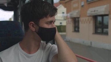 Otobüsten yola odaklan. Maskeli yalnız adam cam otobüs şehrinin yakınında sıkılıyor.