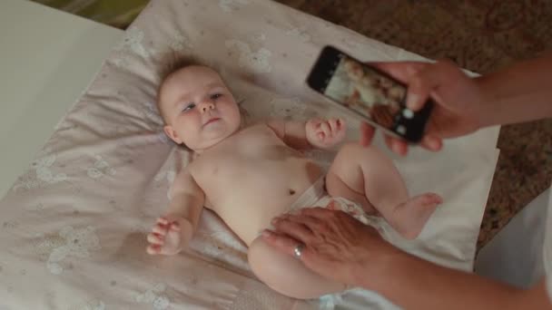 Cute baby. Toddler posing during photo hand holds phone takes photos. — Stock Video