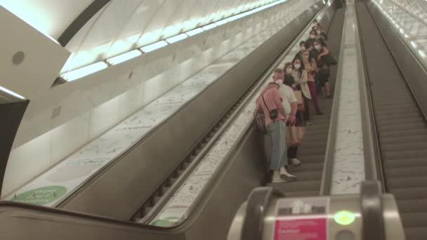 Pasajeros enmascarados en la escalera mecánica del metro. Transporte público covid-19 — Vídeos de Stock
