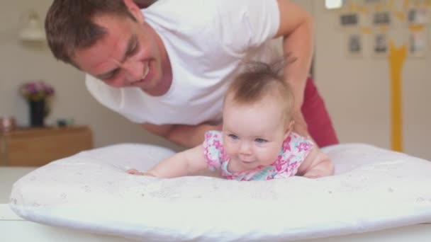 De baby ligt op haar buik onder toezicht. . Gelukkig vader met peuter — Stockvideo