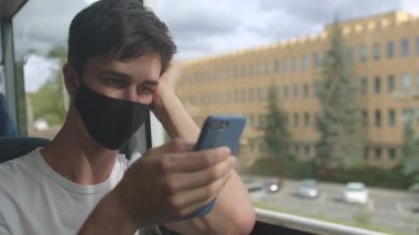 Bir adam toplu taşıma otobüsünde telefon kullanıyor.