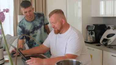 Sakallı adam bilgisayar masası kullanıyor. Partneri bardağı bir kokteyl ile alır.. 