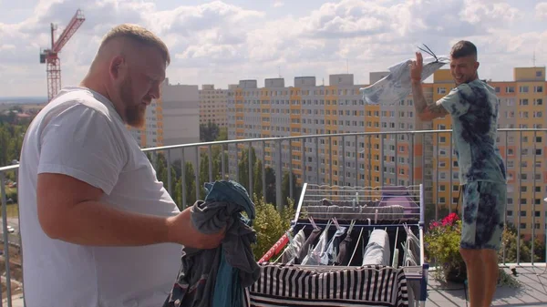 A gay couple hangs up the laundry on the balcony to dry — стоковое фото