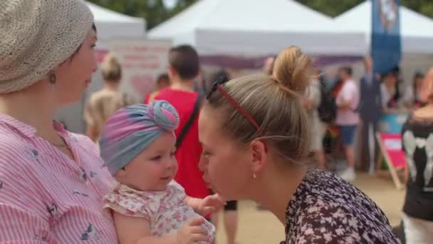 Δύο νεαρές γυναίκες με ένα ευτυχισμένο παιδί σε δημόσιο χώρο, κοντά στο μωρό με τη μητέρα. — Αρχείο Βίντεο