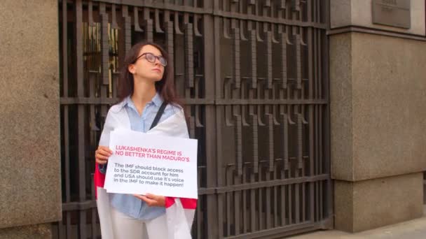Frau hält ein Plakat in der Nähe des Verwaltungsgebäudes in die Höhe — Stockvideo