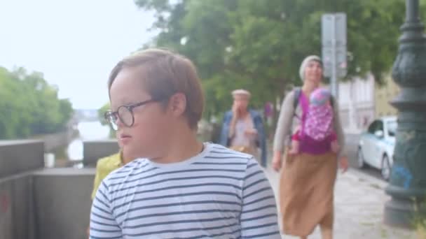 Il utilise des lunettes améliorer sa vision. Down syndrome garçon se déplace famille autour de la ville. — Video