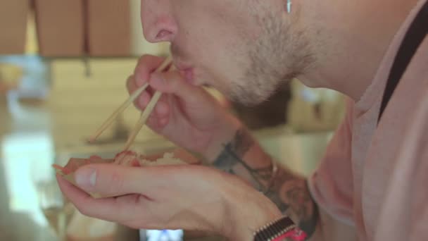 Os homens comem iguarias orientais pauzinhos para pegar pequenos pedaços de comida. Close-up — Vídeo de Stock