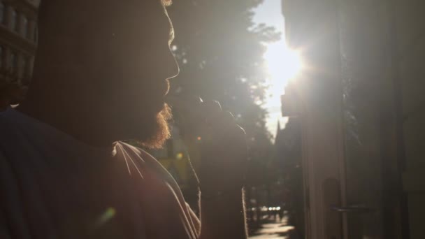 Homme barbu fume cigarette électronique sur fond lumineux soleil ville rue — Video